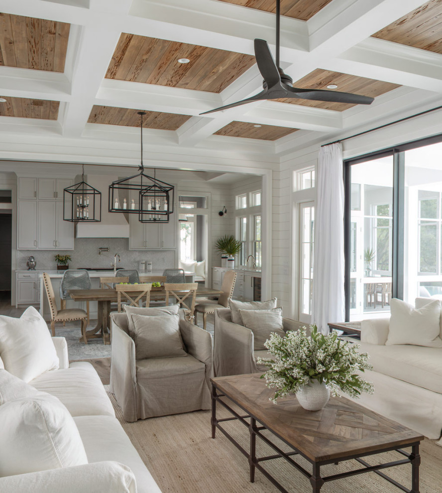 This is an example of a large transitional open concept living room in Other with white walls, light hardwood floors, a standard fireplace, a stone fireplace surround, a wall-mounted tv, beige floor, coffered and planked wall panelling.