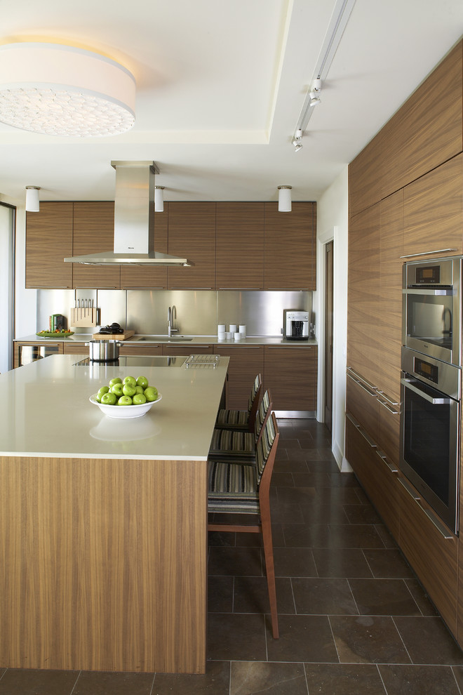 This is an example of a modern kitchen in Atlanta with stainless steel appliances, flat-panel cabinets, medium wood cabinets, quartz benchtops, metallic splashback and metal splashback.
