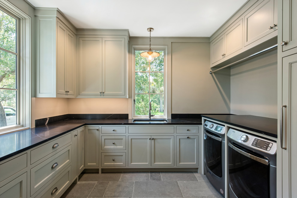 Design ideas for a traditional u-shaped dedicated laundry room in Charleston with an undermount sink, shaker cabinets, distressed cabinets, granite benchtops, black splashback, granite splashback, limestone floors, a side-by-side washer and dryer, brown floor and black benchtop.