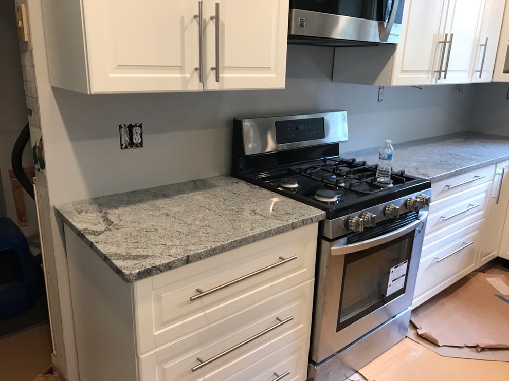 Example of a small l-shaped enclosed kitchen design with an undermount sink, raised-panel cabinets, white cabinets, granite countertops, stainless steel appliances, no island and gray countertops