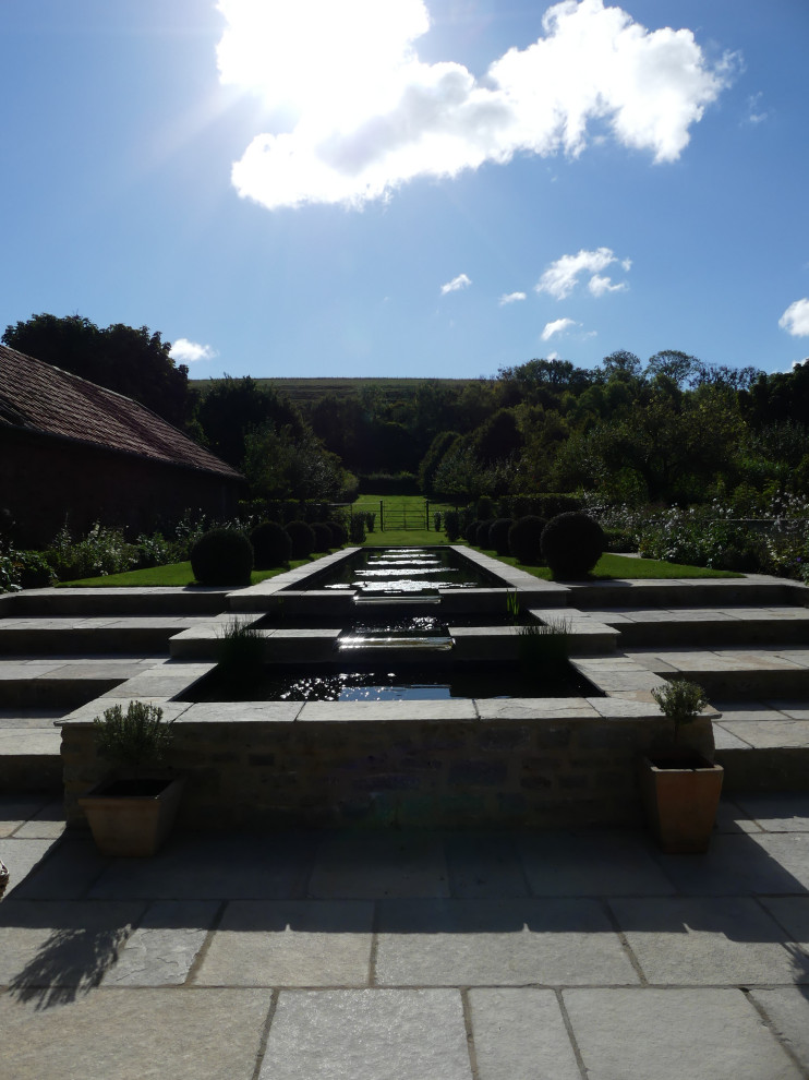 Esempio di un grande giardino formale contemporaneo esposto in pieno sole dietro casa con una cascata e pavimentazioni in pietra naturale