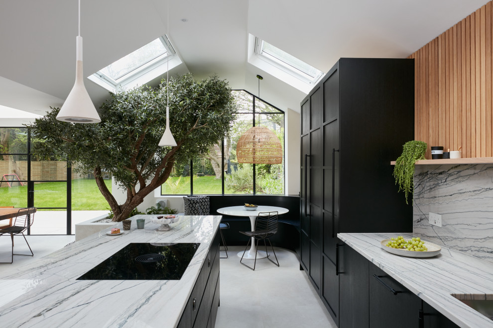 This is an example of a large scandinavian open plan kitchen in London with a drop-in sink, flat-panel cabinets, black cabinets, quartzite benchtops, multi-coloured splashback, black appliances, with island and multi-coloured benchtop.