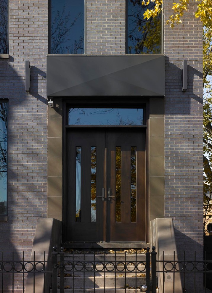 Front door - large modern limestone floor front door idea in Chicago with brown walls and a glass front door