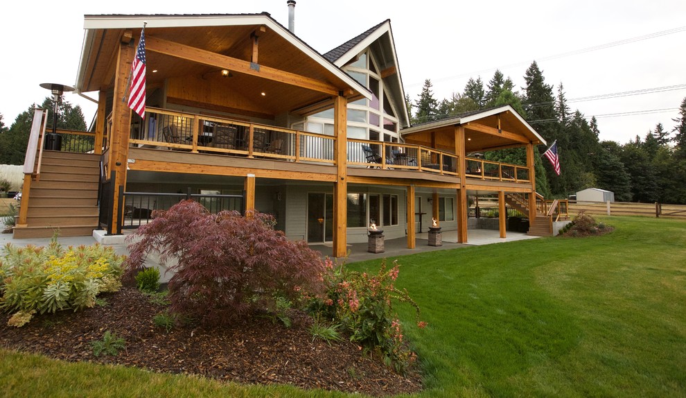 Large mountain style backyard outdoor kitchen deck photo in Seattle with a roof extension