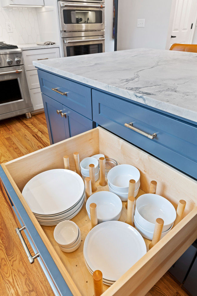 Modern inredning av ett stort grå grått kök, med en undermonterad diskho, skåp i shakerstil, vita skåp, bänkskiva i kvartsit, vitt stänkskydd, stänkskydd i keramik, rostfria vitvaror, ljust trägolv och en köksö