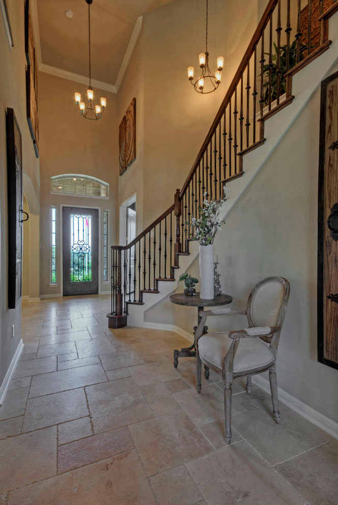 Photo of a mid-sized traditional foyer in Austin with beige walls, limestone floors, a single front door and a glass front door.