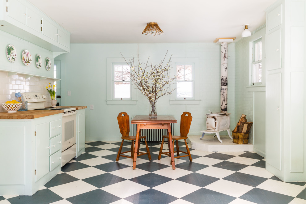 Photo of a traditional kitchen in New York with flat-panel cabinets, turquoise cabinets, wood benchtops, white splashback, subway tile splashback, painted wood floors, no island, multi-coloured floor and brown benchtop.