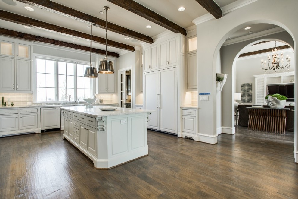 This is an example of an expansive transitional u-shaped eat-in kitchen in Dallas with beaded inset cabinets, white cabinets, marble benchtops, white splashback, medium hardwood floors, with island, brown floor and panelled appliances.