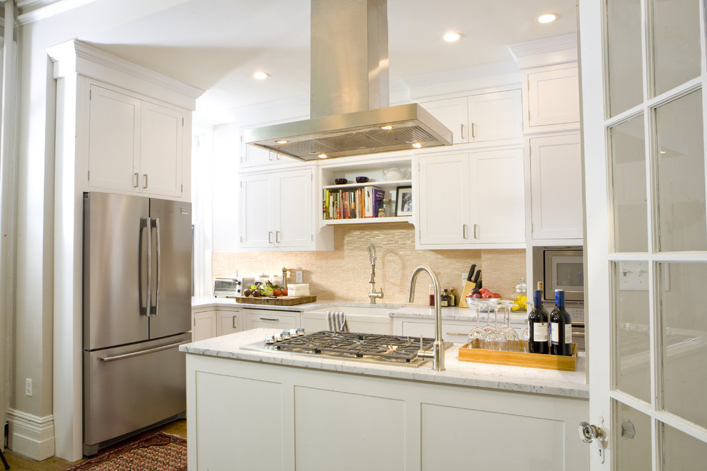 Inspiration for a traditional l-shaped kitchen in New York with stainless steel appliances, a farmhouse sink, shaker cabinets, white cabinets, marble benchtops and beige splashback.