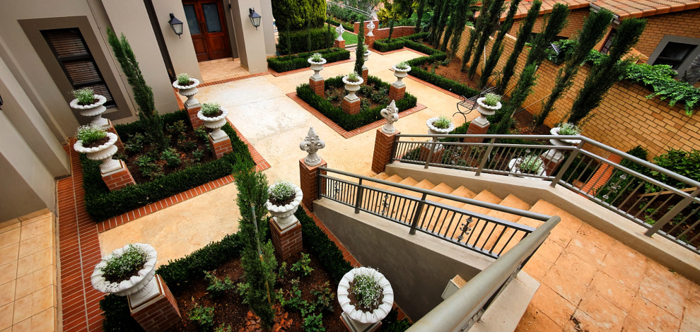 Photo of an expansive mediterranean sloped formal garden in Other with with raised garden bed and brick pavers.