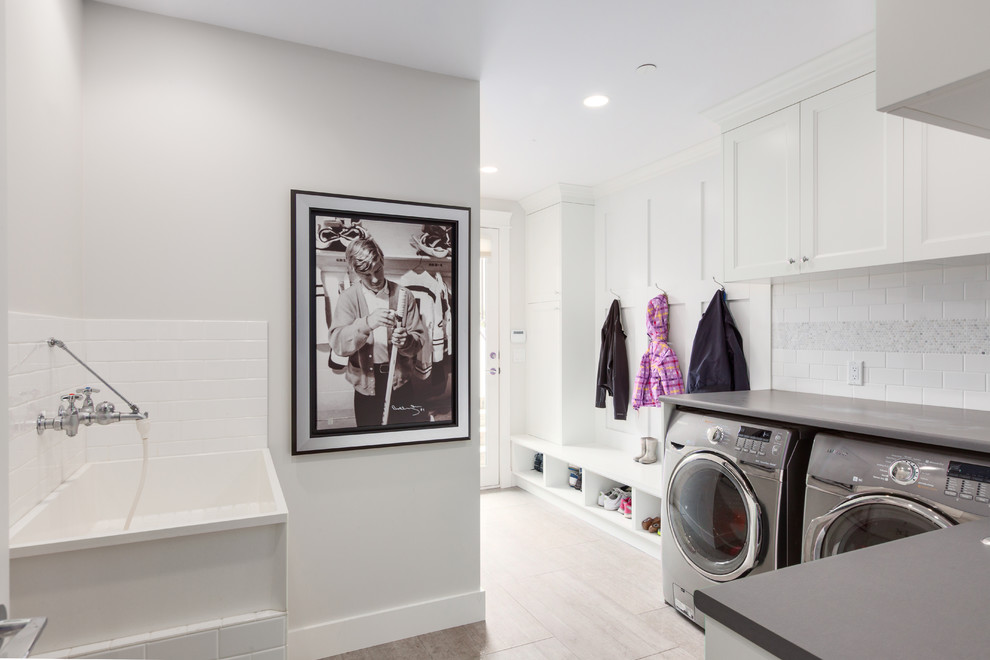 Inspiration for a large transitional u-shaped utility room in Vancouver with an utility sink, shaker cabinets, white cabinets, laminate benchtops, white walls, porcelain floors and a side-by-side washer and dryer.