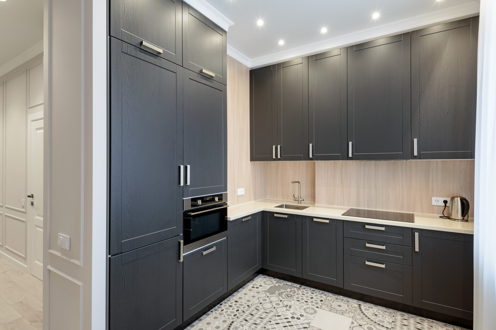 Small transitional l-shaped open plan kitchen in Novosibirsk with a single-bowl sink, raised-panel cabinets, grey cabinets, solid surface benchtops, beige splashback, timber splashback, stainless steel appliances, ceramic floors, no island, grey floor and beige benchtop.