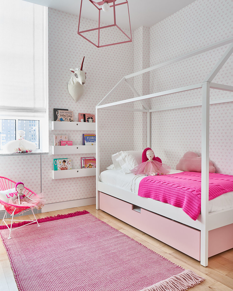 Inspiration for a contemporary kids' bedroom for kids 4-10 years old and girls in New York with pink walls, medium hardwood floors and brown floor.