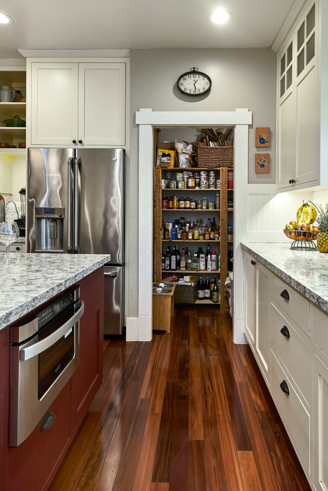 Idéer för att renovera ett mellanstort amerikanskt grå grått l-kök, med en undermonterad diskho, skåp i shakerstil, vita skåp, granitbänkskiva, vitt stänkskydd, stänkskydd i trä, vita vitvaror, mellanmörkt trägolv, en köksö och rött golv