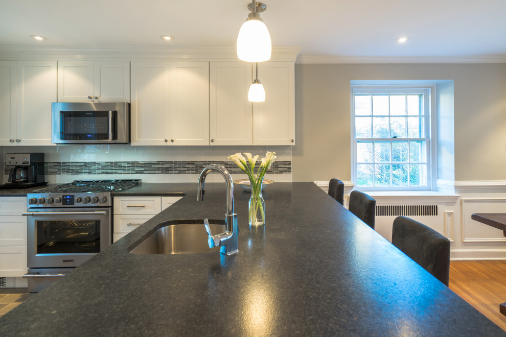 Mid-sized transitional u-shaped eat-in kitchen in Philadelphia with an undermount sink, shaker cabinets, white cabinets, granite benchtops, multi-coloured splashback, mosaic tile splashback, stainless steel appliances, porcelain floors, a peninsula, brown floor and grey benchtop.