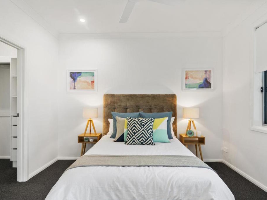 This is an example of a mid-sized beach style guest bedroom in Gold Coast - Tweed with white walls, carpet and grey floor.