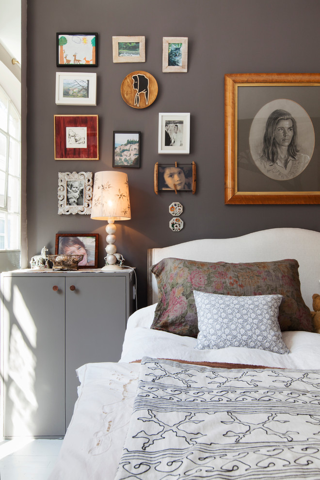 Photo of a mid-sized eclectic guest bedroom in London with grey walls and light hardwood floors.