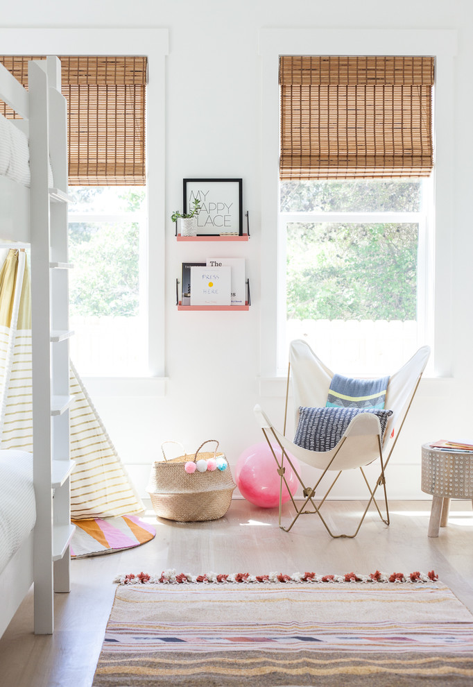 Photo of a beach style kids' room for girls in Miami with white walls and light hardwood floors.