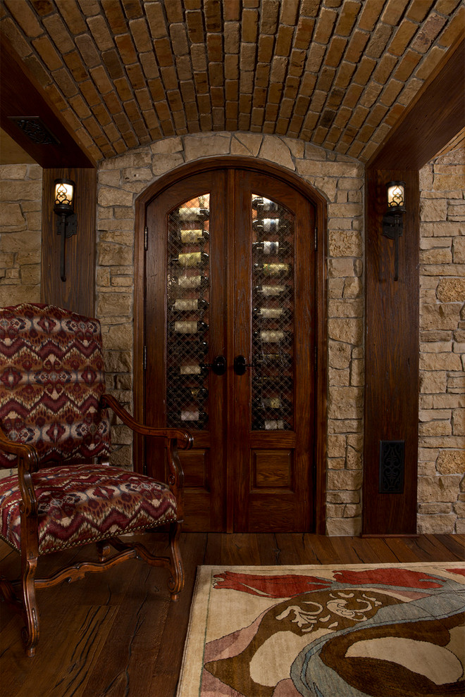 This is an example of a large traditional wine cellar in Detroit with dark hardwood floors, display racks and brown floor.