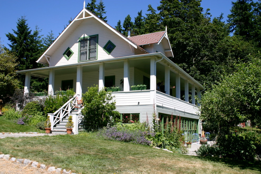 Photo of a mid-sized country three-storey white exterior in Seattle with wood siding and a gable roof.