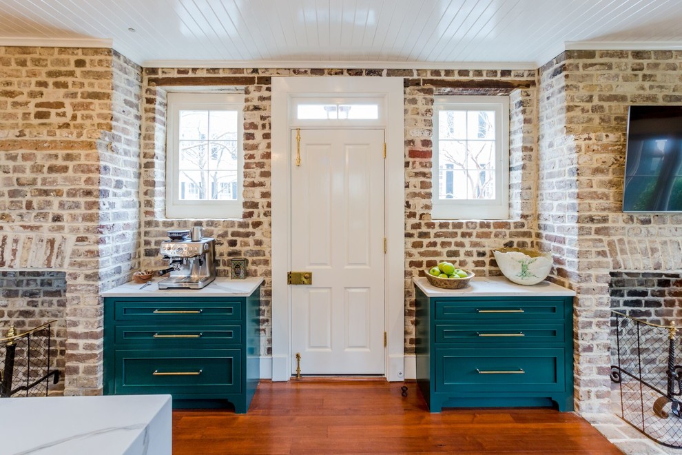 Mid-sized transitional kitchen pantry in Charleston with a farmhouse sink, beaded inset cabinets, green cabinets, quartz benchtops, brown splashback, brick splashback, stainless steel appliances, medium hardwood floors, with island, brown floor and white benchtop.