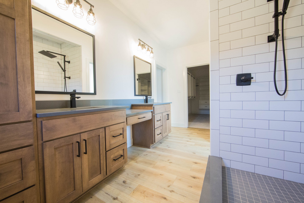 Medium sized traditional ensuite bathroom in Indianapolis with recessed-panel cabinets, brown cabinets, an alcove shower, white tiles, metro tiles, white walls, light hardwood flooring, a submerged sink, granite worktops, brown floors, a hinged door, white worktops, double sinks and a freestanding vanity unit.