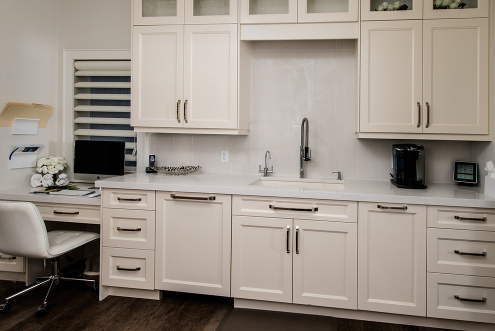 This is an example of a contemporary galley separate kitchen in Vancouver with an undermount sink, recessed-panel cabinets, white cabinets, quartz benchtops, white splashback, subway tile splashback and panelled appliances.