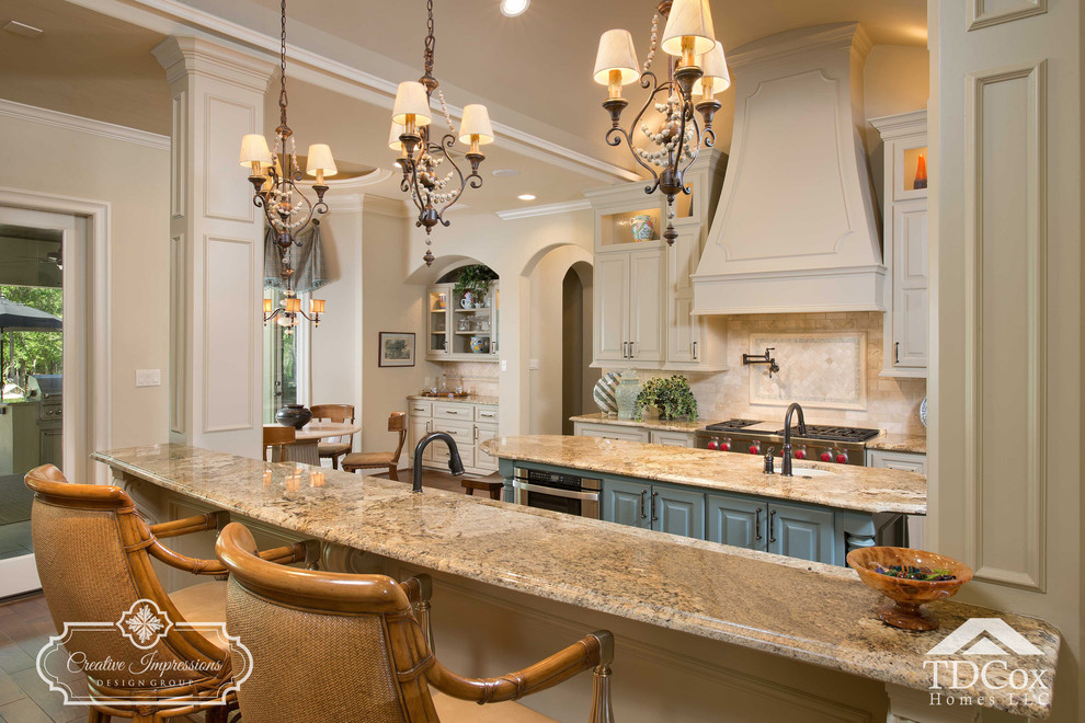 Open concept kitchen - large transitional u-shaped medium tone wood floor and beige floor open concept kitchen idea in Houston with an undermount sink, shaker cabinets, white cabinets, granite countertops, beige backsplash, travertine backsplash, black appliances and an island