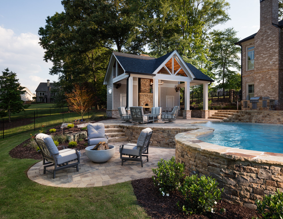Photo of a large traditional backyard custom-shaped natural pool in Atlanta with a pool house and concrete pavers.