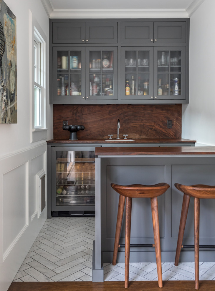 Transitional galley home bar in Sacramento with an undermount sink, glass-front cabinets, grey cabinets, wood benchtops, white floor and brown benchtop.