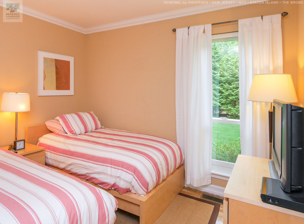 ニューアークにある中くらいなおしゃれな客用寝室 (オレンジの壁、無垢フローリング、暖炉なし) のインテリア