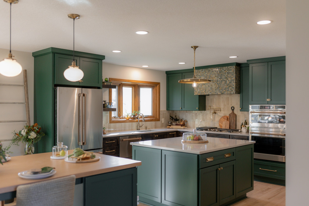 Inspiration for a mid-sized transitional l-shaped light wood floor and brown floor eat-in kitchen remodel with an undermount sink, recessed-panel cabinets, green cabinets, quartz countertops, beige backsplash, terra-cotta backsplash, stainless steel appliances, two islands and beige countertops