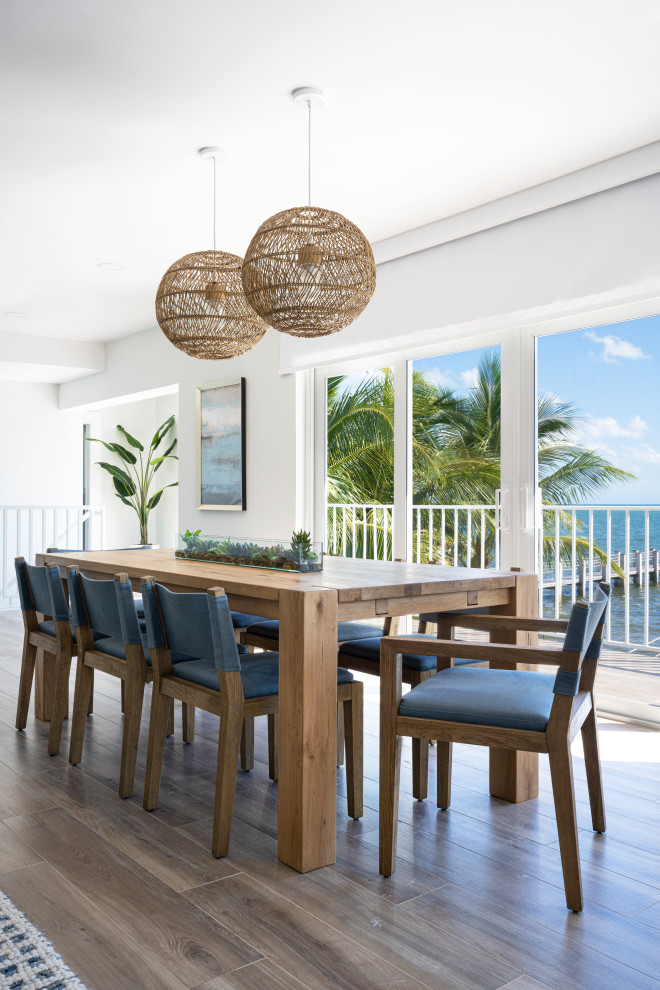 Photo of a mid-sized beach style open plan dining in Miami with white walls, porcelain floors and beige floor.