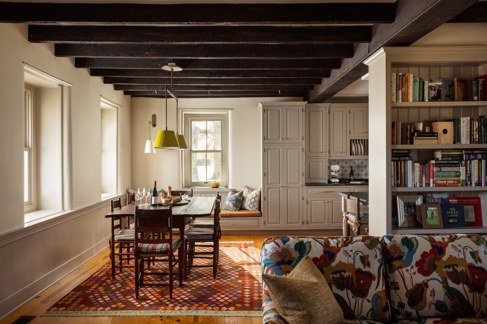 Example of a farmhouse medium tone wood floor, brown floor and exposed beam great room design in Philadelphia with white walls