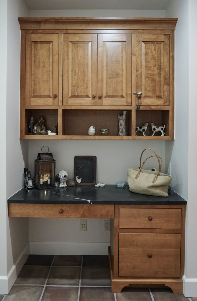 Example of a mid-sized classic u-shaped ceramic tile and brown floor enclosed kitchen design with an undermount sink, shaker cabinets, medium tone wood cabinets, solid surface countertops, stainless steel appliances and an island