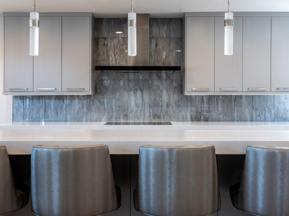 Large transitional l-shaped eat-in kitchen in New York with a drop-in sink, flat-panel cabinets, grey cabinets, quartz benchtops, blue splashback, glass tile splashback, stainless steel appliances, light hardwood floors, with island, grey floor and white benchtop.