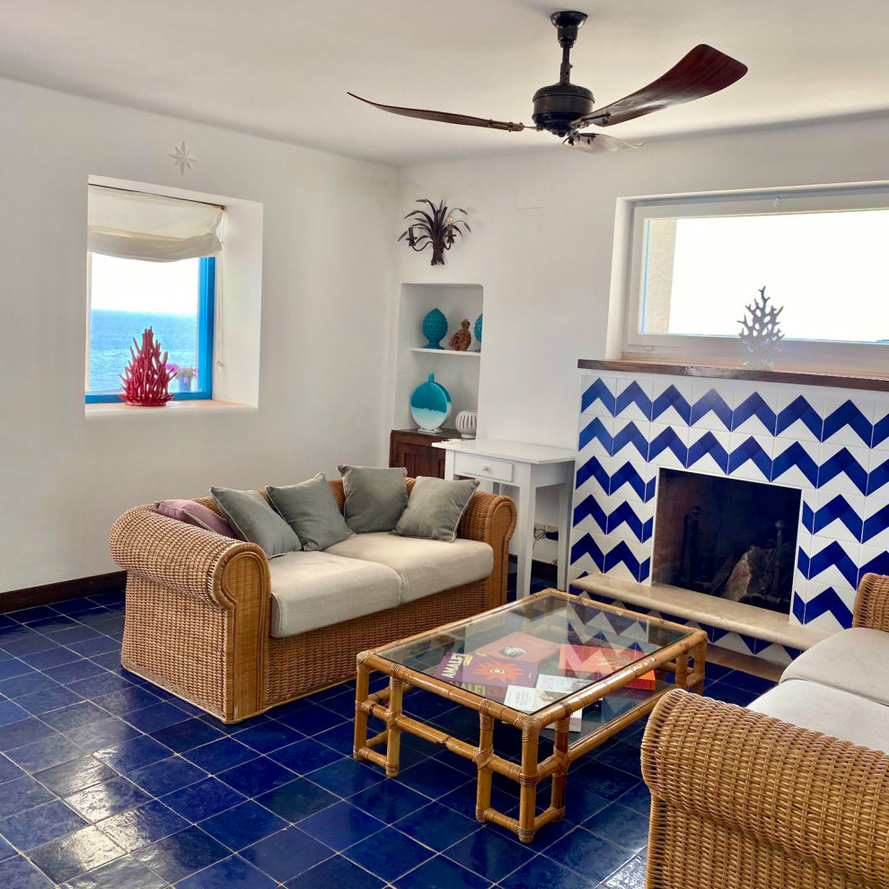 Идея дизайна: большая открытая гостиная комната в морском стиле с белыми стенами, полом из керамической плитки, стандартным камином, фасадом камина из плитки и синим полом