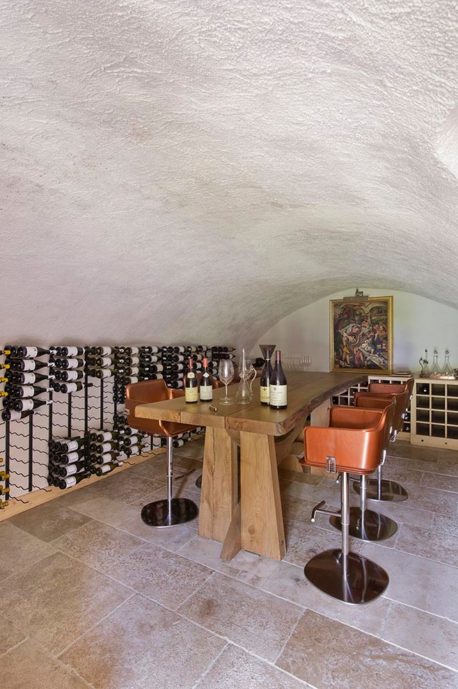 Inspiration for a mid-sized transitional wine cellar in Marseille with limestone floors and display racks.