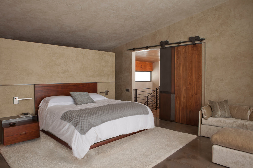 Photo of a large modern loft-style bedroom in New York with beige walls, limestone floors and no fireplace.
