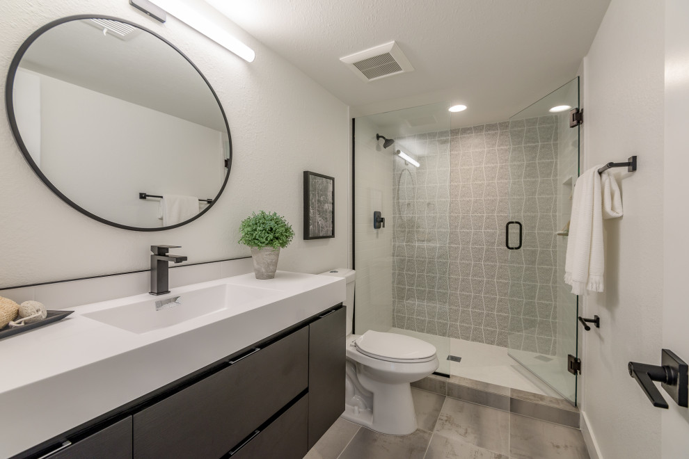 Bild på ett funkis vit vitt badrum, med släta luckor, grå skåp, en dusch i en alkov, grå kakel, vita väggar, ett integrerad handfat, grått golv och dusch med gångjärnsdörr