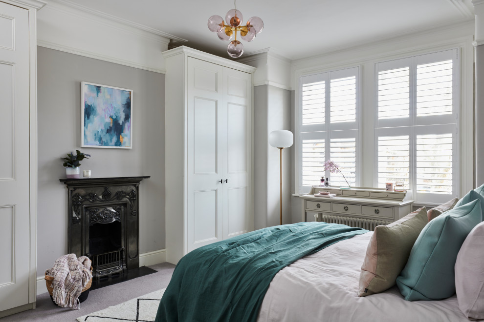 Inspiration for a mid-sized transitional master bedroom in Kent with grey walls, carpet, a standard fireplace, a metal fireplace surround and grey floor.