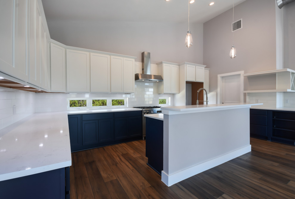 Design ideas for a large modern u-shaped open plan kitchen in Austin with a farmhouse sink, shaker cabinets, blue cabinets, quartz benchtops, white splashback, porcelain splashback, stainless steel appliances, dark hardwood floors, with island, brown floor, white benchtop and vaulted.