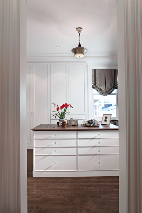 Large transitional gender-neutral walk-in wardrobe in Toronto with beaded inset cabinets, white cabinets, dark hardwood floors and brown floor.