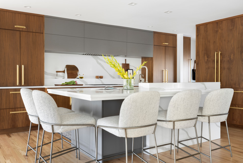 Mid-sized contemporary l-shaped eat-in kitchen in Denver with a single-bowl sink, flat-panel cabinets, medium wood cabinets, quartz benchtops, yellow splashback, engineered quartz splashback, panelled appliances, light hardwood floors, with island and white benchtop.