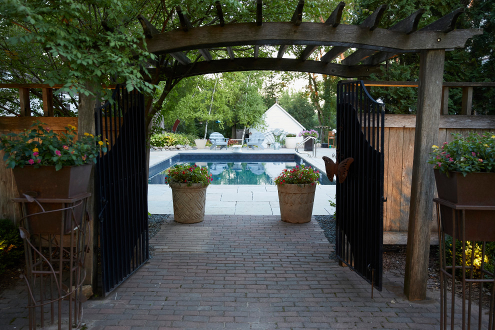 Пример оригинального дизайна: большой спортивный, прямоугольный ландшафтный бассейн на заднем дворе в стиле кантри с покрытием из каменной брусчатки