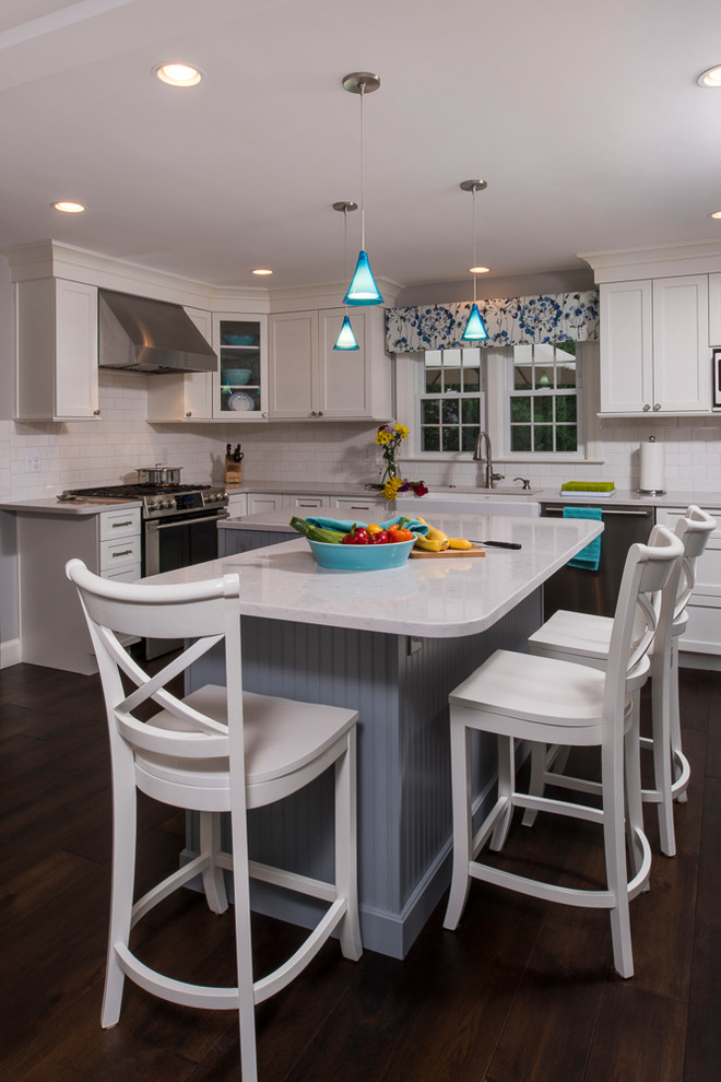 Kitchen - transitional l-shaped dark wood floor and brown floor kitchen idea in Boston with a farmhouse sink, flat-panel cabinets, white cabinets, quartz countertops, white backsplash, ceramic backsplash, stainless steel appliances and an island