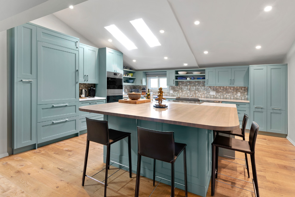 Design ideas for a transitional l-shaped kitchen in Other with a farmhouse sink, recessed-panel cabinets, turquoise cabinets, quartz benchtops, multi-coloured splashback, mosaic tile splashback, with island, brown floor, white benchtop, stainless steel appliances and medium hardwood floors.