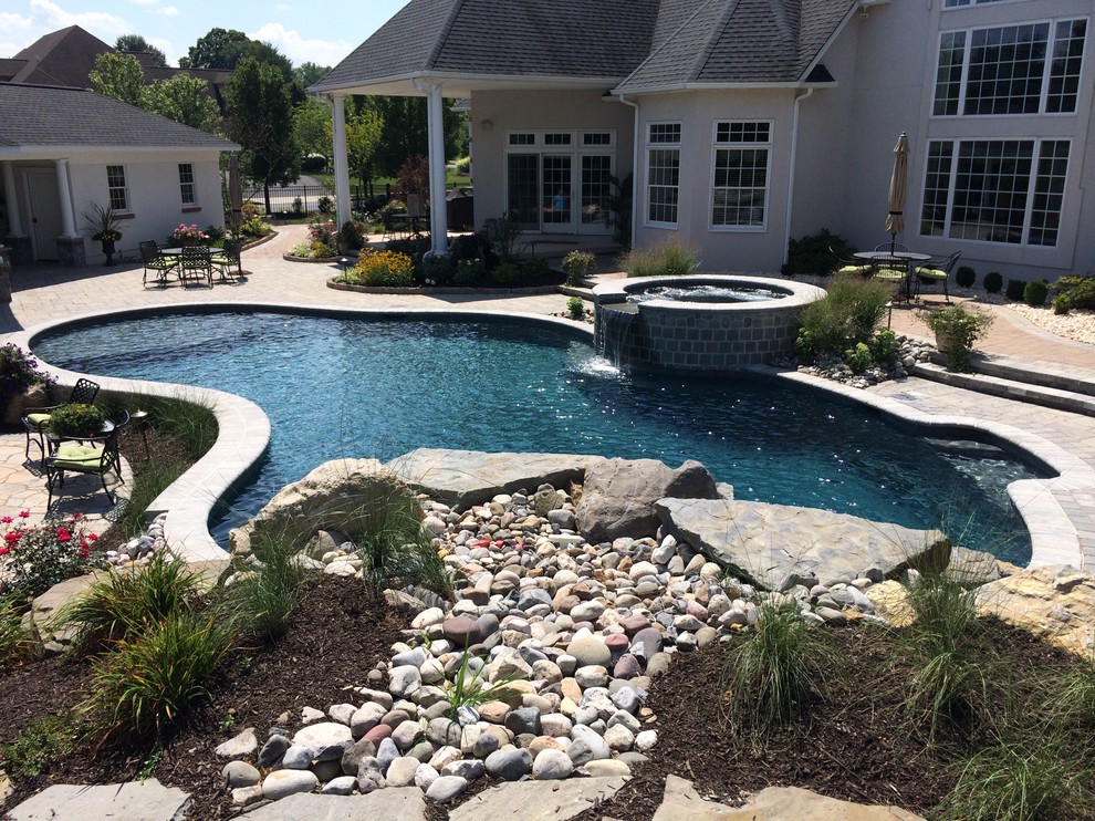 Inspiration for a large traditional backyard custom-shaped natural pool in Philadelphia with concrete pavers.
