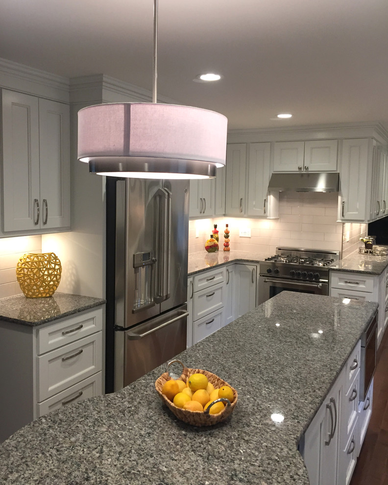 Kitchen - transitional galley dark wood floor kitchen idea with an undermount sink, flat-panel cabinets, white cabinets, granite countertops, white backsplash, porcelain backsplash, stainless steel appliances and an island