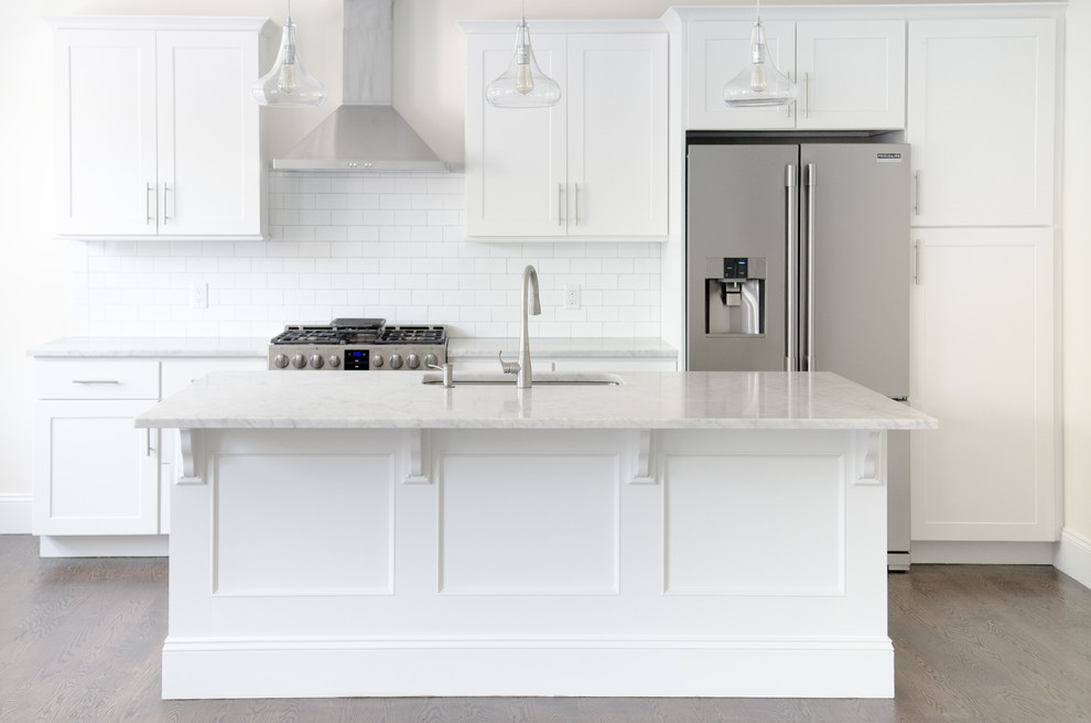 Design ideas for a large transitional single-wall kitchen in New York with an undermount sink, shaker cabinets, white cabinets, quartz benchtops, white splashback, subway tile splashback, stainless steel appliances, dark hardwood floors, with island and brown floor.